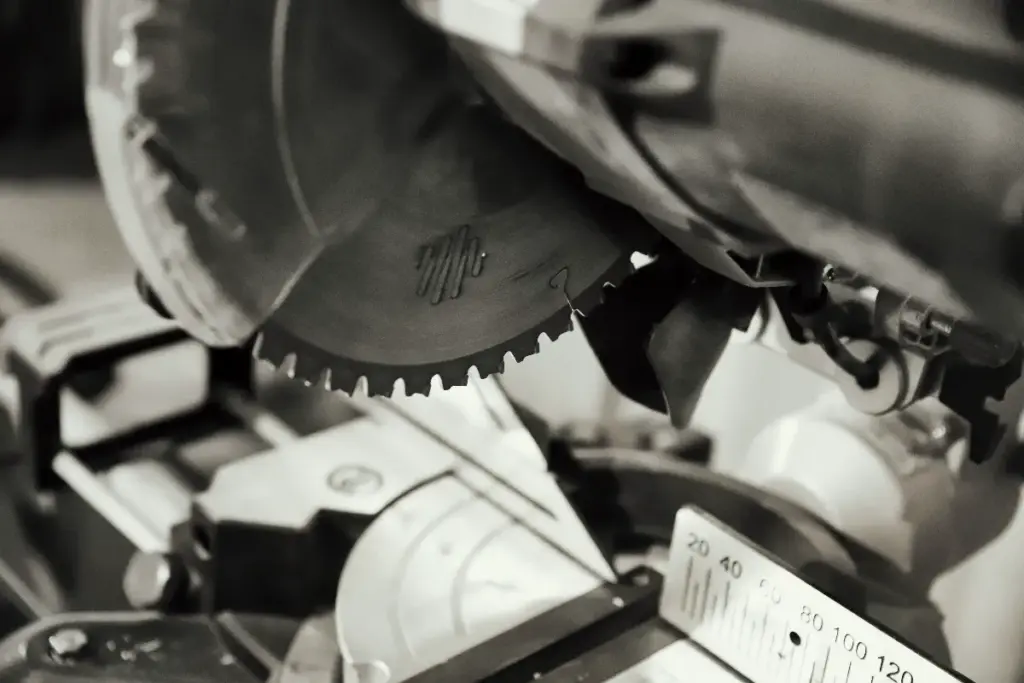 Close-up black and white photo of a miter saw blade and cutting teeth.