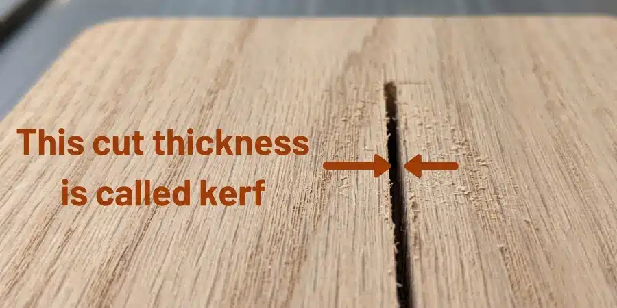 Close-up of a saw cut in a wooden board with text and arrows illustrating that the cut thickness is called kerf.